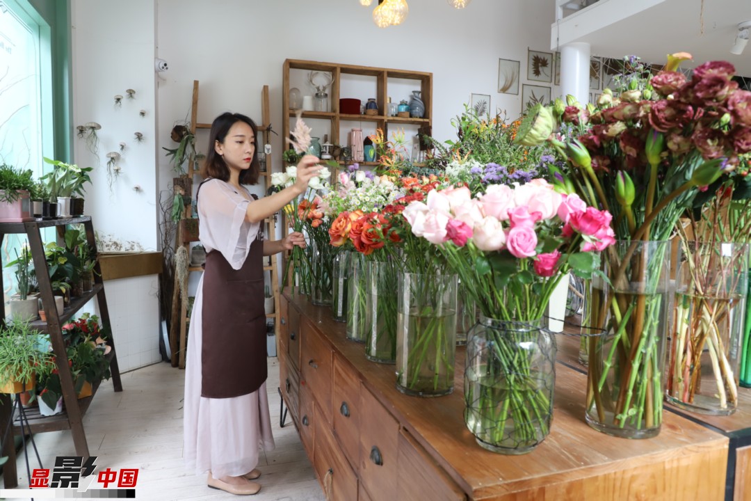 王黎媛是一名河南姑娘，在昆明念完大學(xué)后，就再也舍不下春城的藍(lán)天陽光、青山碧水，更舍不下這里的四時(shí)繁花，于是就干脆留了下來，成了一名媒體人。2017年的時(shí)候又毅然辭去工作，創(chuàng)業(yè)開起了花店，成了都市里的一名“花房姑娘”。圖為王黎媛在自己的花店中整理鮮花。新華網(wǎng) 周亞平/攝 念新洪/文